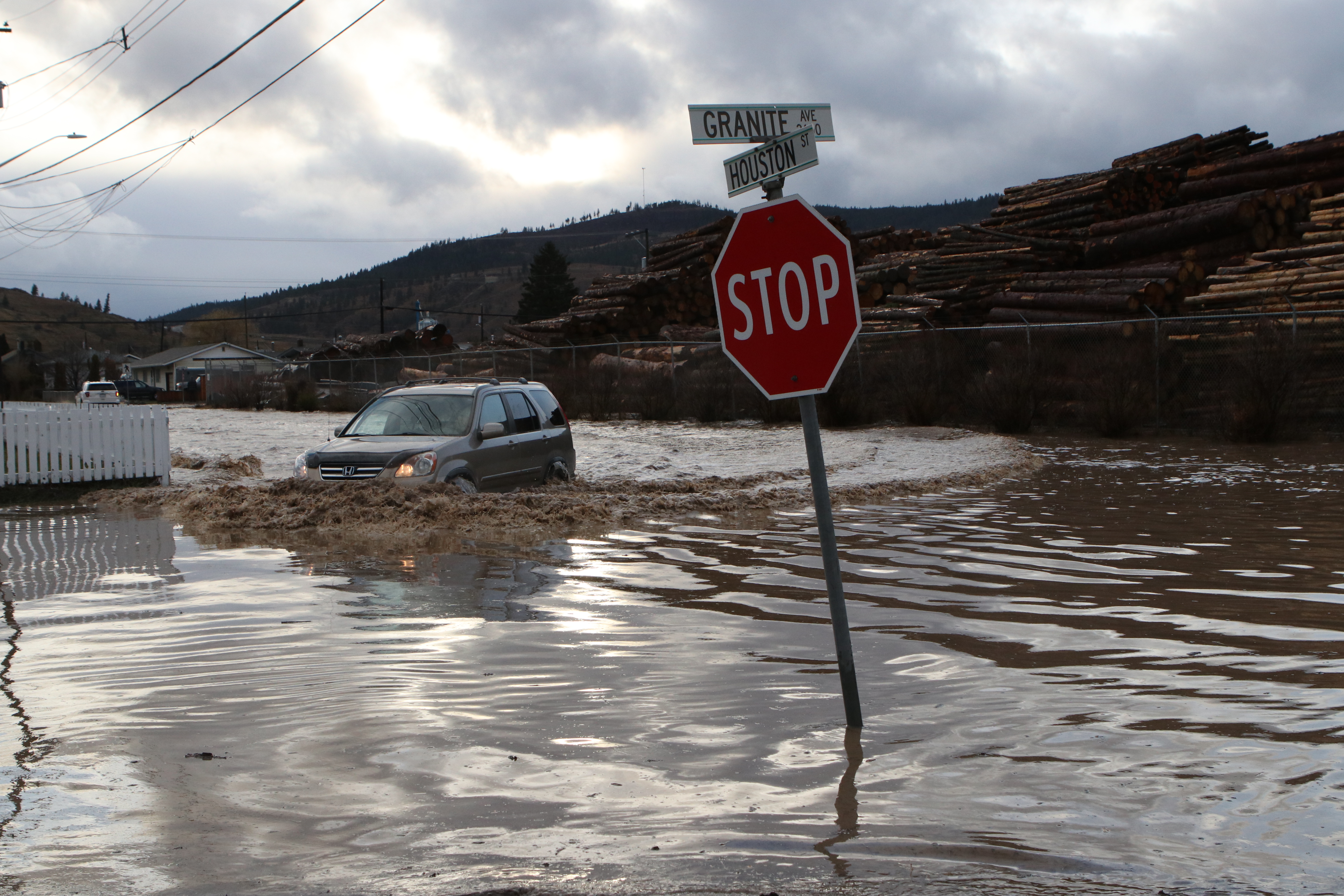 A car drives down a flooded Houston Street in Merritt, B.C., on Nov. 15, 2021. (Photo by Aaron Hemens for the Globe and Mail)