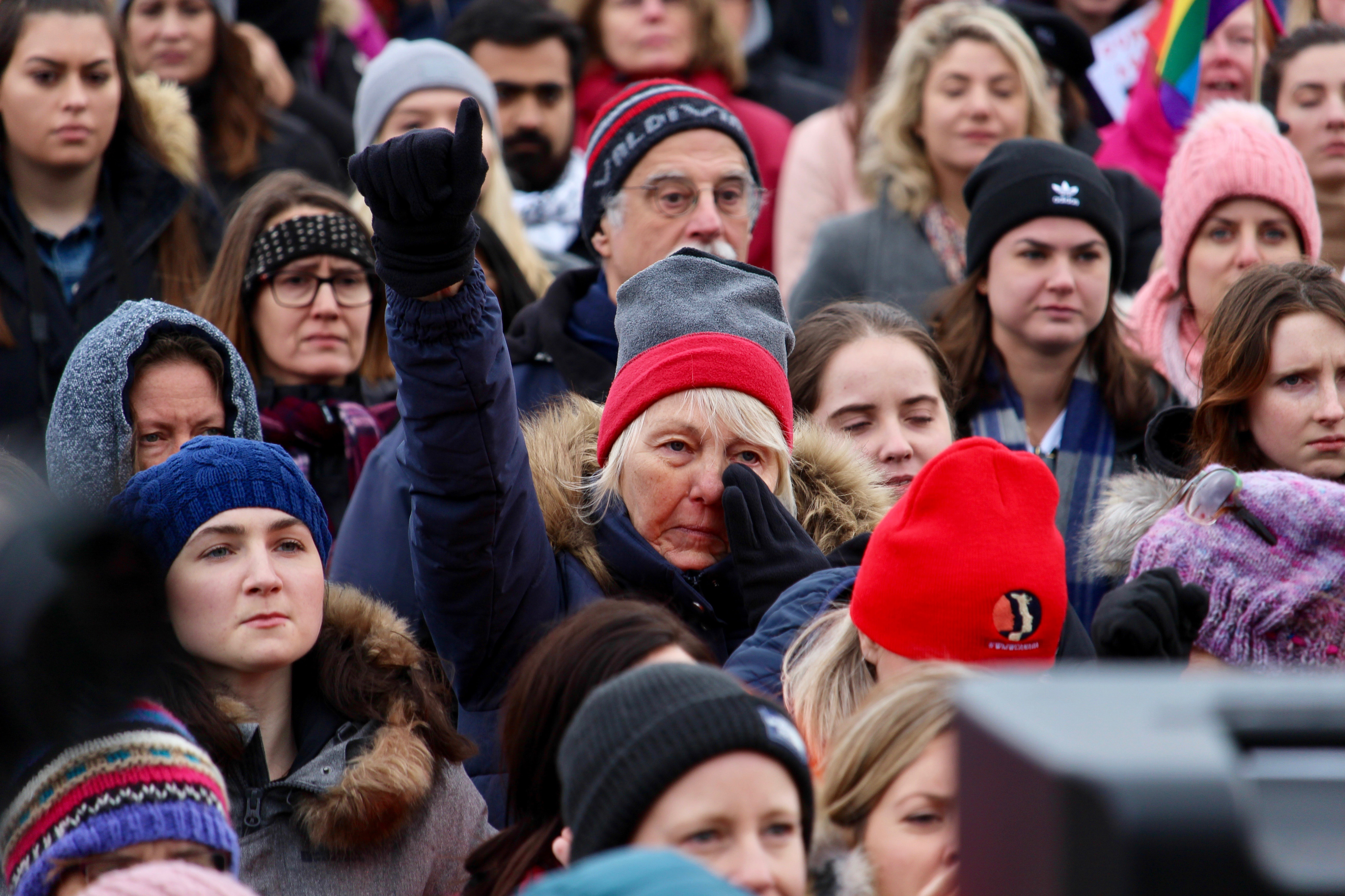 A woman wipes her eye as she raises her fist in the air during Ottawa's second annual Women's March at Parliament Hill on Jan. 20, 2018. Ottawa was one of the hundreds of cities around the world to host a women's march that day, which began in 2017 following Donald Trump's inauguration as U.S. president. (Photo by Aaron Hemens for Centretown News)